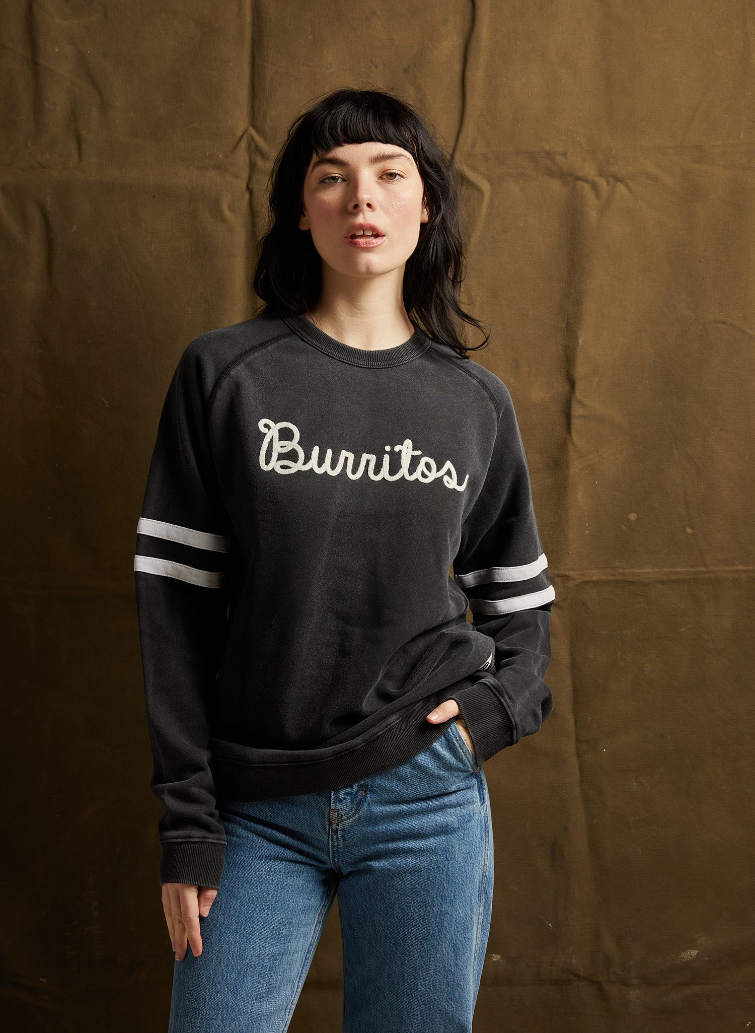 Female Model wearing Pyknic Burritos Chainstitch Crewneck in Vintage Black, showcasing chainstitch embroidery and sleeve stripes.