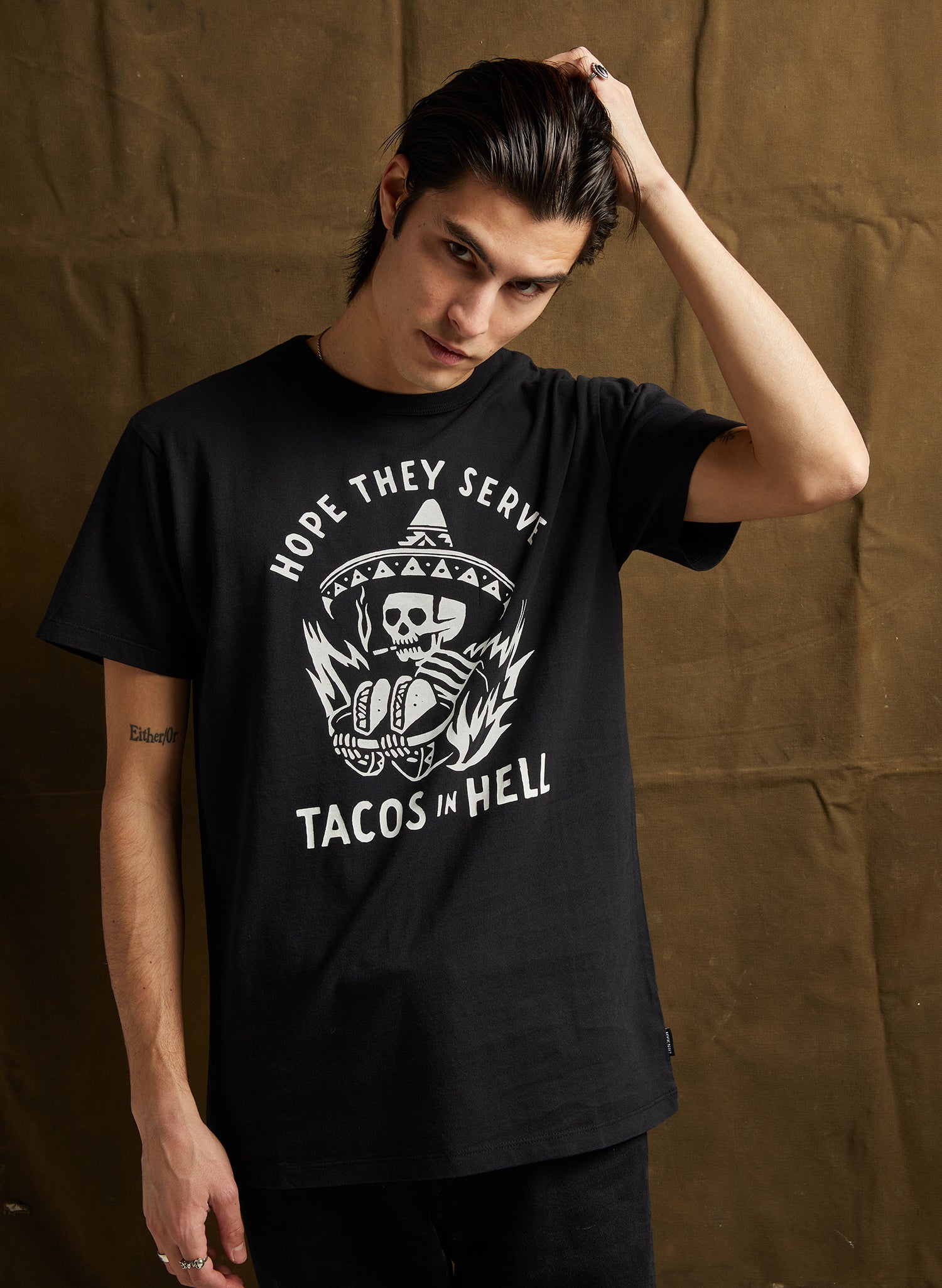 men - Male model in Hope They Serve Tacos in Hell Tee in Black with bold graphic print, made of soft cotton blend.