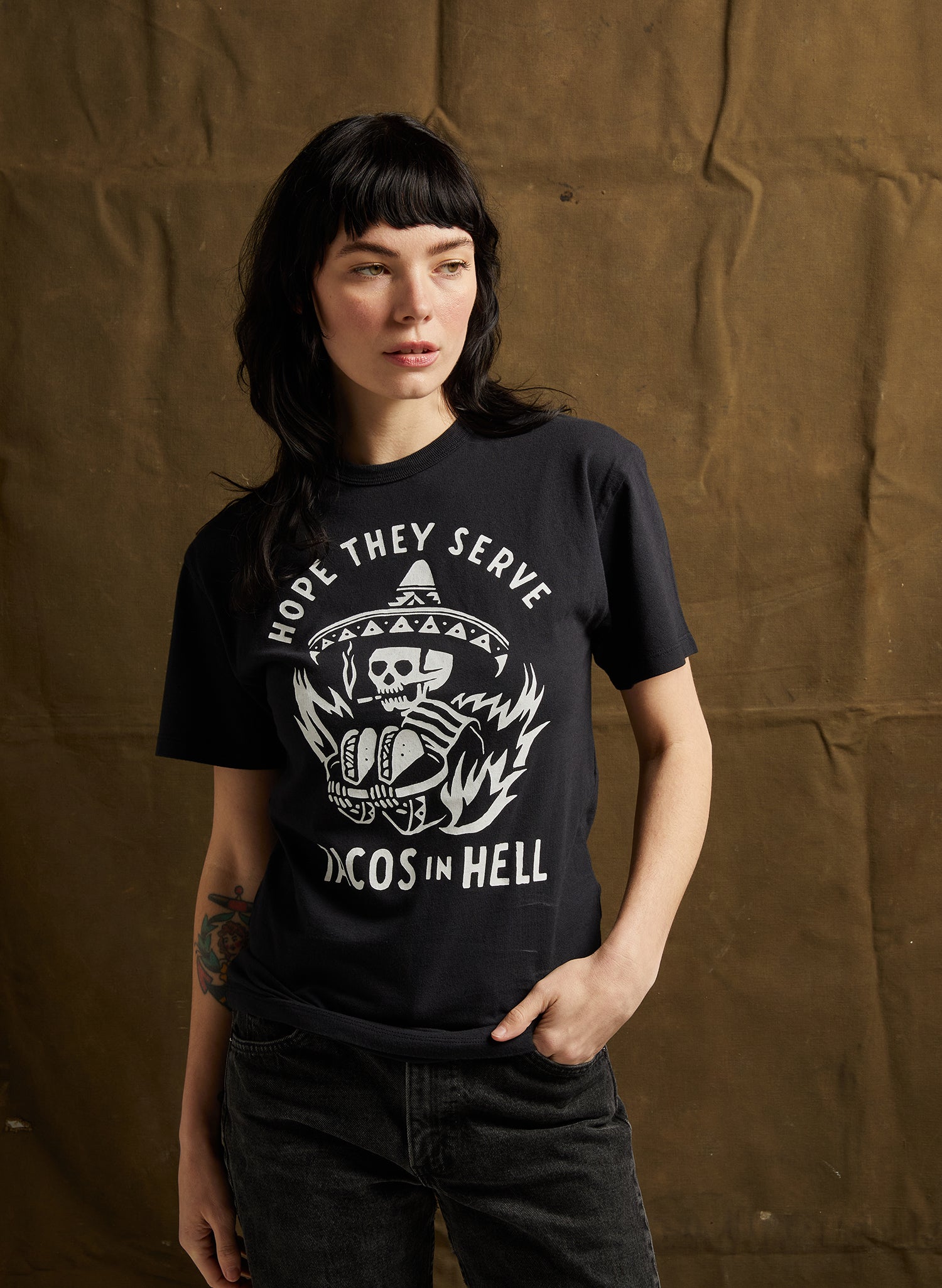 women - Female model in Hope They Serve Tacos in Hell Tee in Black with bold graphic print, made of soft cotton blend.