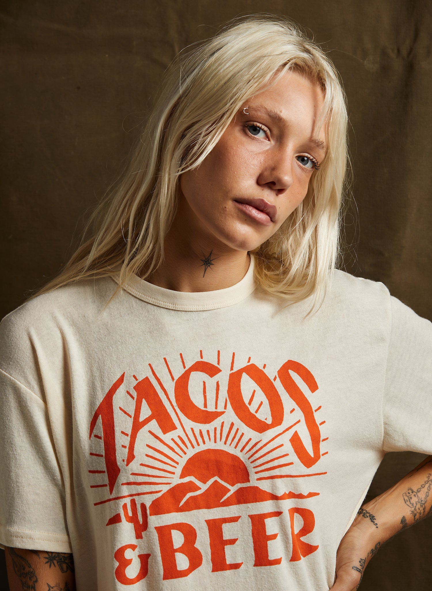 Woman wearing the unisex Tacos and Beer Graphic Tee with desert sunrise design on soft cotton-rayon blend cream t-shirt.