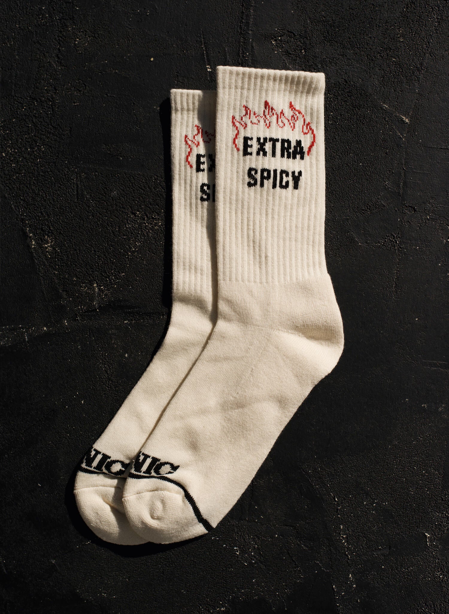 Close-up of Pyknic Extra Spicy Socks, featuring snarky 'Extra Spicy' knit design on Ecru crew socks.
